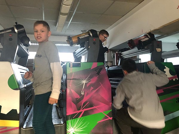 Kinder klettern auf farbenfrohe Druckmaschinen und erkunden sie