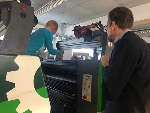 Kind klettert auf Druckmaschine, Mann beobachtet aufmerksam