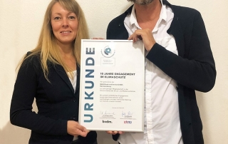 Betriebsleiterin und Geschäftsführer der MHD halten Urkunde für 10 Jahre Klimaschutz-Engagement