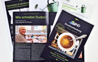 Mehrere Magazine auf weißem Tisch, Titelthema: Druckverkostung & Samenpapier