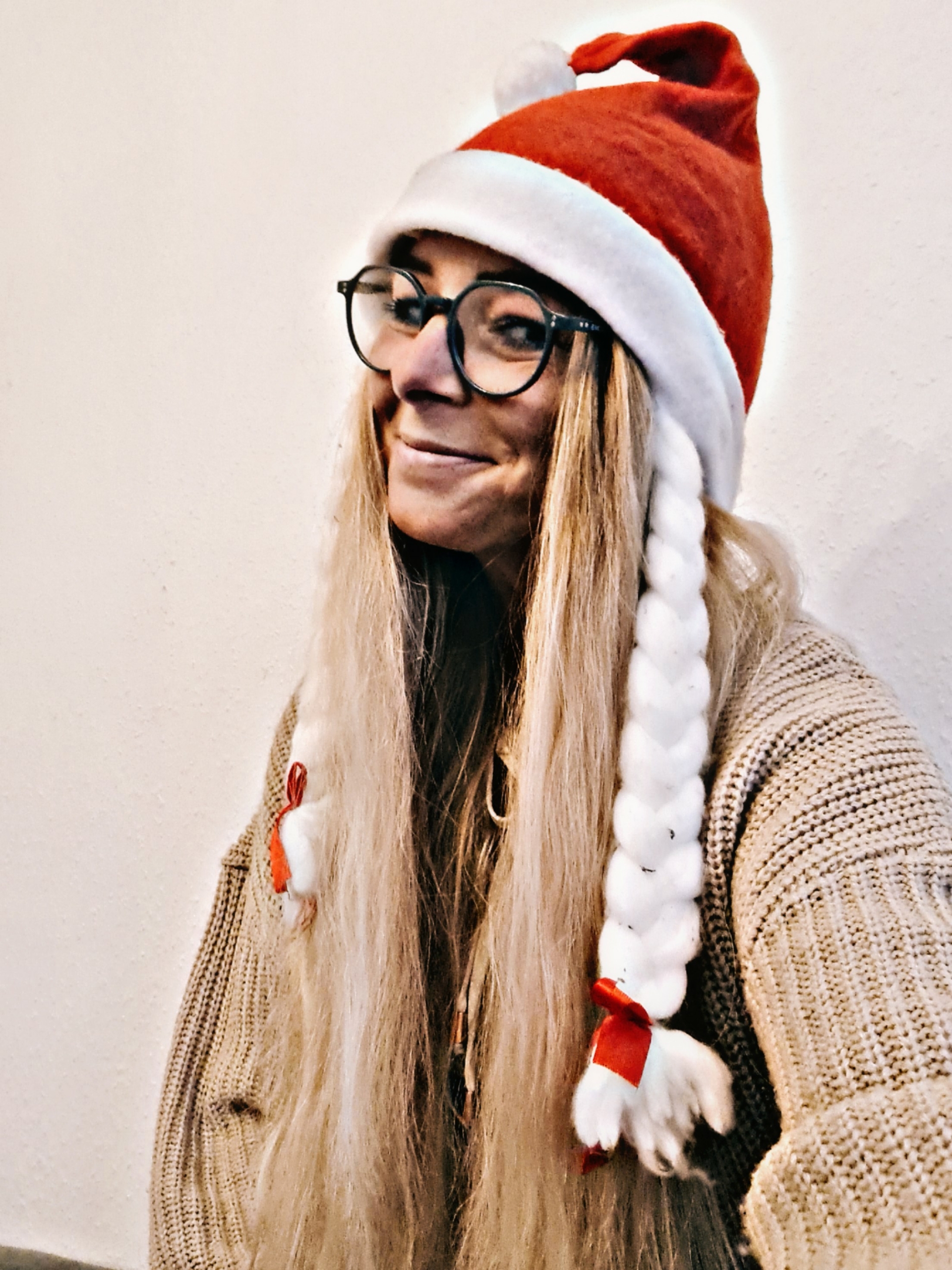 Frau mit langer blonder Perücke und Weihnachtsmütze, lächelt in die Kamera