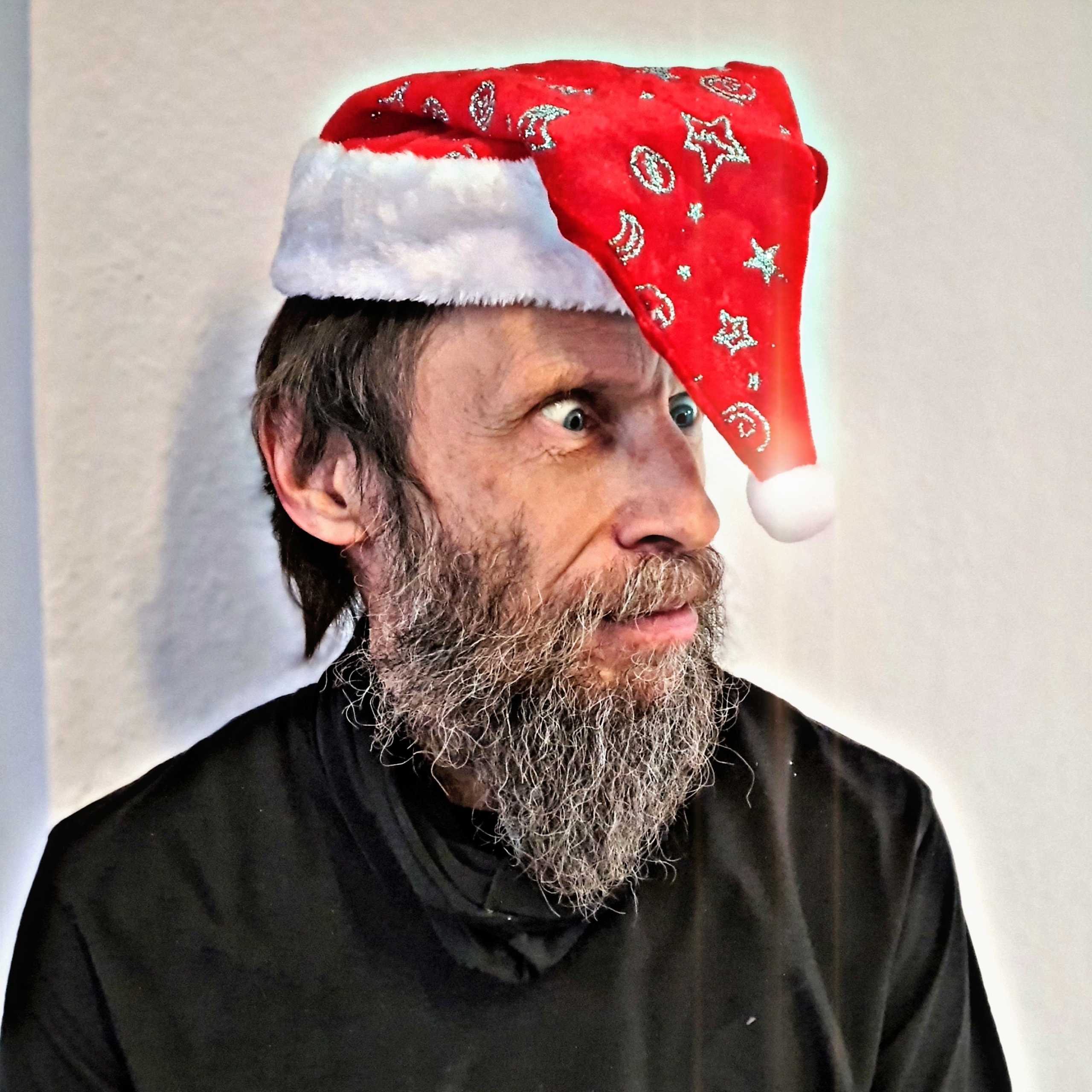 Bärtiger Mann mit schwarzem Oberteil und schräg sitzender Nikolausmütze