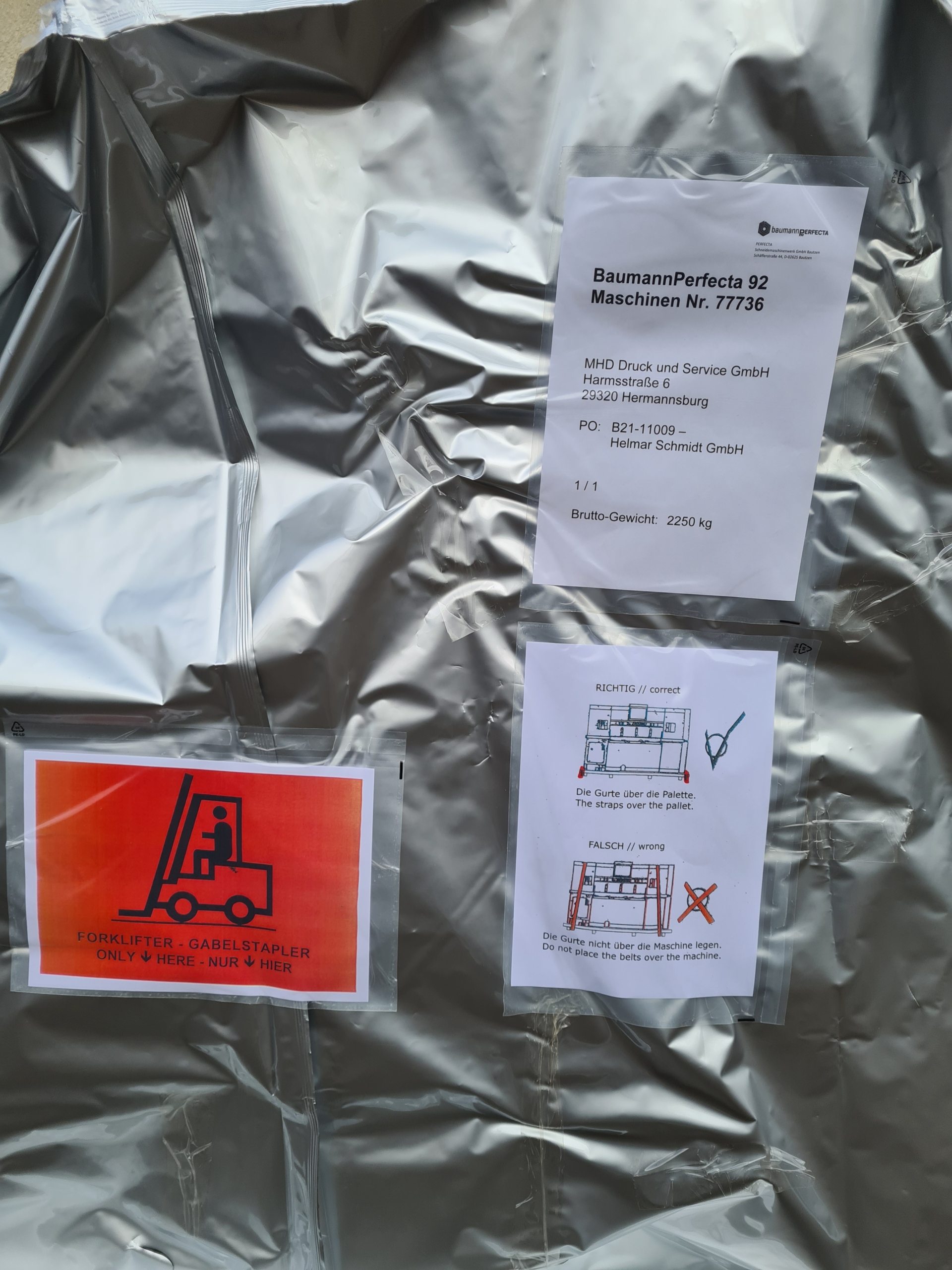 Detailaufnahme: Hinweise und Versandlabel auf silberner Maschinenverpackung