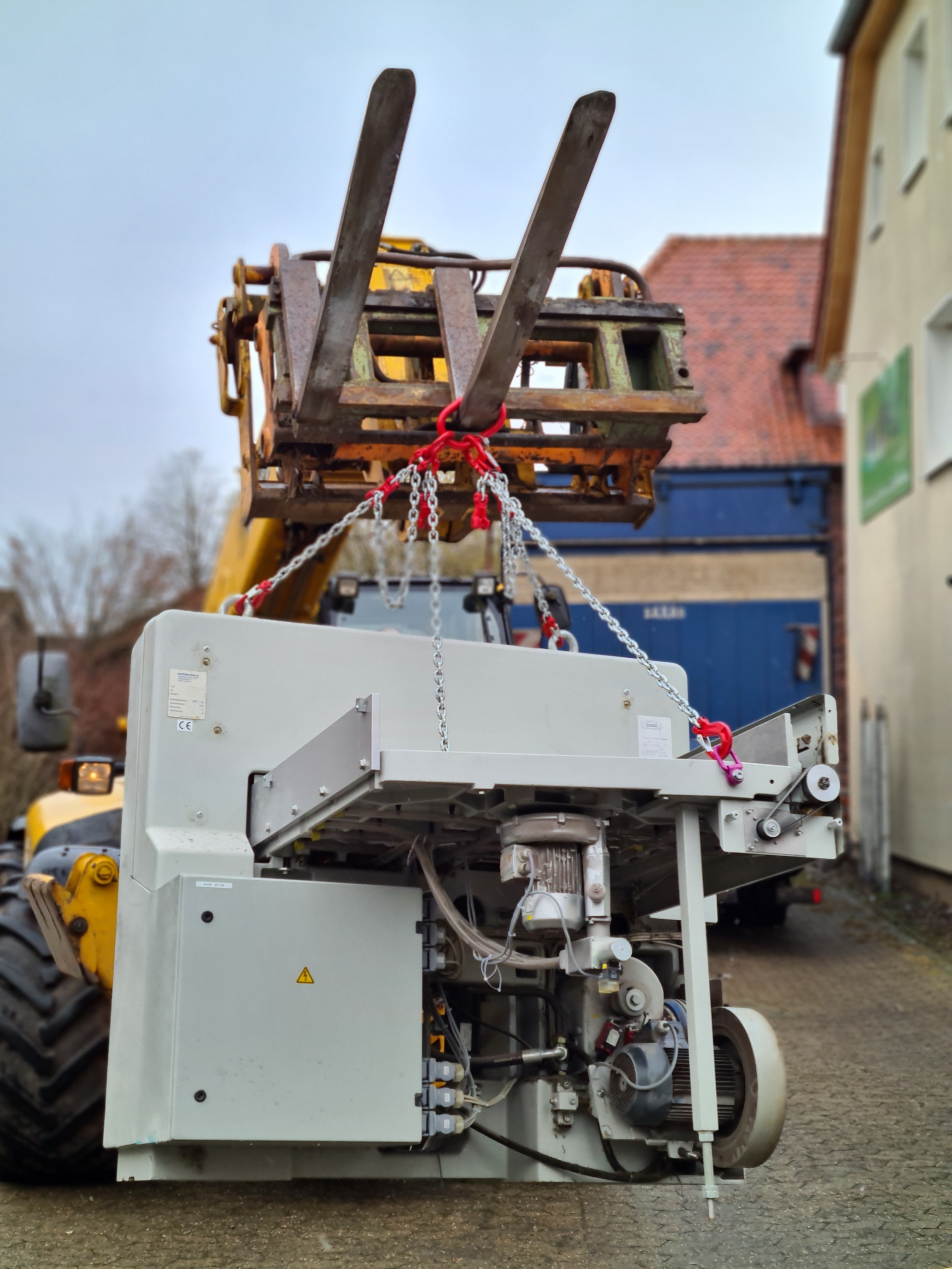 Maschine wird mit Ketten und Teleskoplader angehoben und transportiert