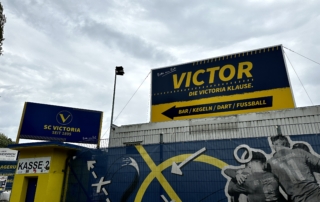 Eingangsbereich des SC Victoria mit gelb-blauer Beschilderung und Wandgrafik